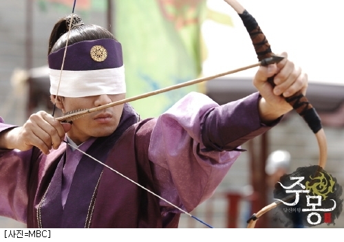 blindfolded Chinese man shooting arrow