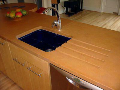 drain grooves next to blue kitchen sink in orange concrete countertop
