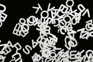 white plastic letters scattered on black background