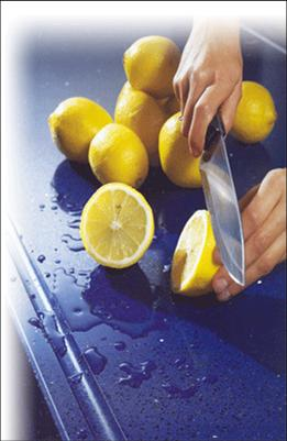 woman's hands cutting lemons on bright blue engineered quartz countertop