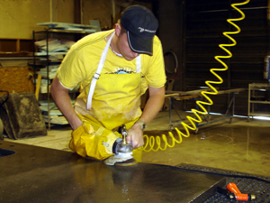 man using pneumatic air grinder in concrete countertop shop