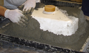 hand packing in stiff concrete countertop mix onto integral concrete sink mold