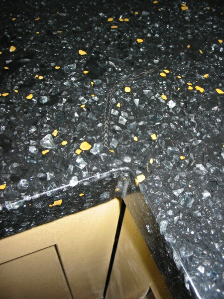 closeup of corner of black concrete countertop with glass metal and yellow stone decorative aggregate embedded