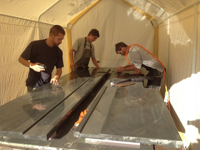 men grinding concrete countertop slabs in tent