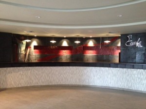 long curved black concrete countertop in bar with red glass tile