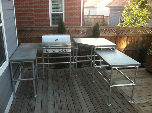 multilevel gray concrete countertop in outdoor kitchen with metal tube legs