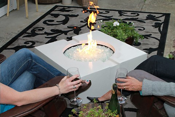 couple with wine glasses sitting by white concrete fire pit