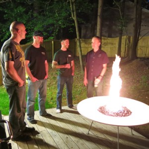 four men standing by round white concrete fire pit