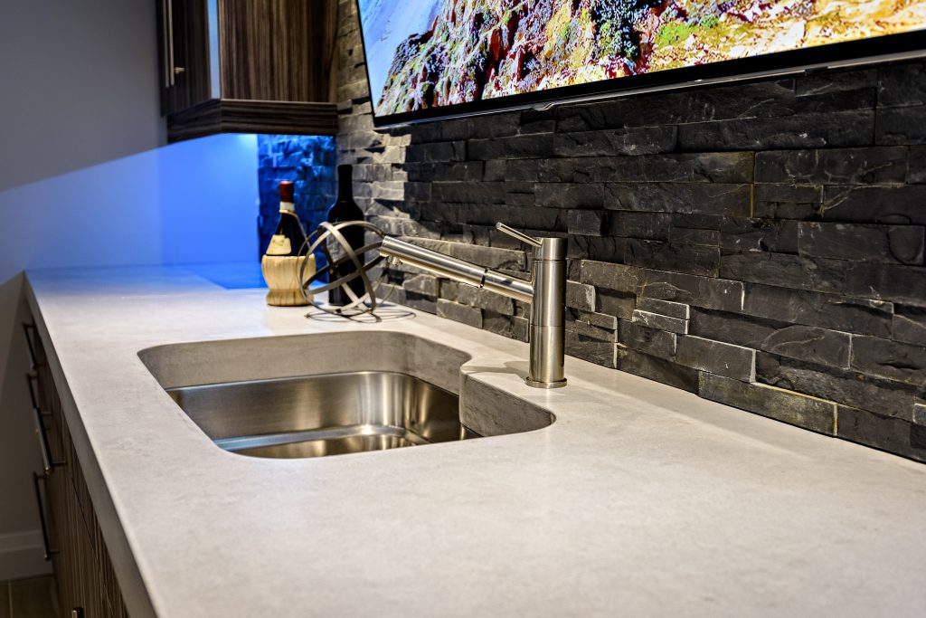 concrete countertop with bar sink and stacked stone backsplash